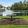 a picnic table on a lawn by a pond