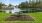 a picnic table on a lawn by a pond