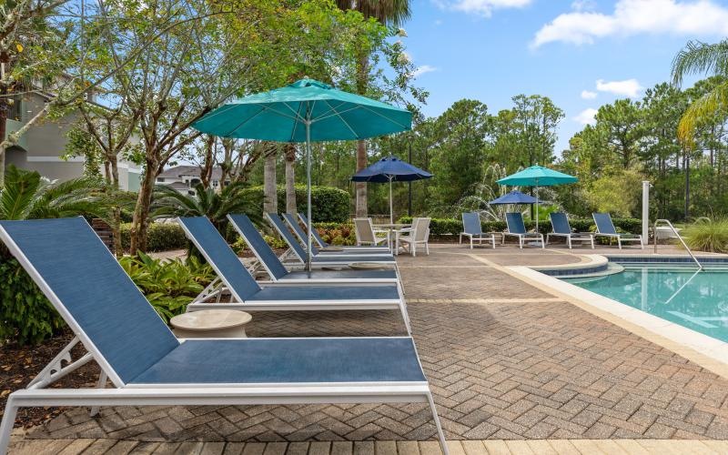 a pool with lounge chairs and umbrellas by it